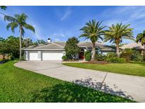 Beautiful home featuring palm trees, a well-manicured lawn, and a three car garage at 3398 Pinnacle S Ct, Palm Harbor, FL 34684