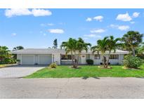 Charming single-story home with three-car garage, lush lawn, and tropical palm tree landscaping at 636 Tarawitt Dr, Longboat Key, FL 34228