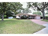 Charming single-story home with a well-manicured lawn, brick driveway, and mature trees at 1001 Brookside Dr, Clearwater, FL 33764