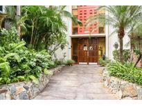 Inviting condo entrance with lush landscaping, stone pathway, and warm wood doors at 1012 Pearce Dr # 304, Clearwater, FL 33764