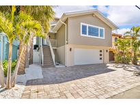 Two-story home featuring a neutral color palette, a two-car garage, and mature landscaping at 12312 Lagoon Ln, Treasure Island, FL 33706