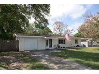 Charming one-story home with a well-manicured lawn and an attached garage, displaying the American flag at 1345 Springdale St, Clearwater, FL 33755