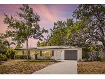Charming single-story home with a well-manicured lawn, inviting blue front door, and convenient garage at 1410 San Charles Dr, Dunedin, FL 34698