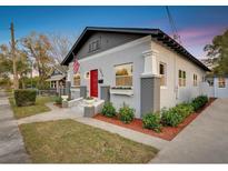 Charming home featuring a red door, landscaped yard, flower boxes, and an American flag at 1515 E 31St Ave, Tampa, FL 33610