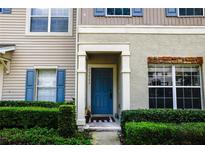 Inviting entryway with a blue front door framed by manicured hedges and a beige textured wall at 15733 Fishhawk Falls Dr, Lithia, FL 33547
