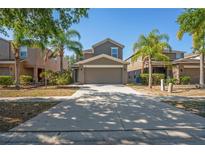 Inviting two-story home featuring a spacious driveway, a two car garage and lush tropical landscaping at 7350 Lumber Port Dr, Ruskin, FL 33573