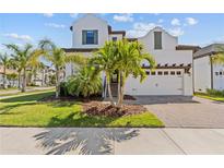 Stunning two-story home showcasing a manicured lawn and lush palm trees, creating a tropical paradise at 923 Seagrape Dr, Ruskin, FL 33570