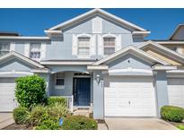 Charming two-story townhome featuring a one-car garage, blue exterior, and well-maintained landscaping at 9807 Carlsdale Dr, Riverview, FL 33578