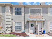 Charming townhome with well-maintained lawn, decorative door awning, and neutral color palette at 14053 Notreville Way, Tampa, FL 33624