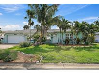 Charming home featuring a light-blue exterior, lush landscaping, and mature palm trees at 2310 Sunrise Se Dr, St Petersburg, FL 33705