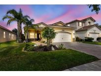 Charming single-Gathering home featuring a well-manicured lawn, tropical landscaping, and a two-car garage at 2632 Tarragona Way, Wesley Chapel, FL 33543
