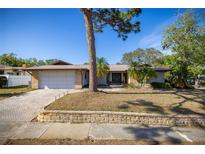 Charming single-story home with a well-manicured lawn, mature trees, brick driveway, and a two-car garage at 2932 Sweetgum S Way, Clearwater, FL 33761