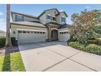 Stunning two-story home with a three-car garage, stone accents and a well-manicured lawn at 3211 Grassglen Pl, Wesley Chapel, FL 33544