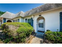 Charming home featuring an arched front door, blue shutters, and lush green landscaping at 4242 Sheldon Pl, New Port Richey, FL 34652