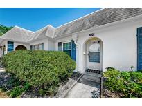 Charming home featuring a white exterior, arched doorway and blue shutters surrounded by mature landscaping at 4242 Sheldon Pl, New Port Richey, FL 34652