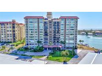 A full exterior shot of a large condo building surrounded by manicured lawns and mature palm trees at 736 Island Way # 303, Clearwater Beach, FL 33767
