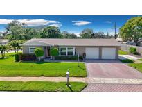Charming single-story home with well-manicured lawn, brick driveway, and two-car garage at 8392 137Th Ln, Seminole, FL 33776