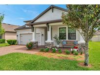 Charming home featuring a covered porch with stone accents and a well-manicured lawn at 12280 Lyon Pine Ln, Odessa, FL 33556