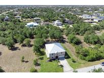 Scenic aerial view of a home with a light metal roof surrounded by lush trees and other houses in the neighborhood at 14319 Morristown Ave, Port Charlotte, FL 33981