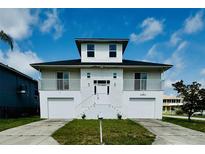 Charming waterfront home with two-car garage, white facade, and inviting front entry at 15621 Bertram Dr, Hudson, FL 34667
