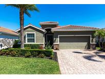 Charming single-story home featuring a tile roof, manicured landscaping, and a brick paver driveway at 2855 Oriole Dr, Sarasota, FL 34243