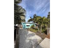 Charming blue cottage with a gravel driveway surrounded by lush tropical landscaping at 4501 26Th S Ave, St Petersburg, FL 33711