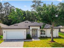 Charming single-story home with a well-manicured lawn, modern white exterior, and inviting entryway at 5051 Gevalia Dr, Brooksville, FL 34604