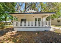 Charming home featuring a welcoming covered front porch with white picket fence and lush trees overhead at 8215 N 12Th St, Tampa, FL 33604