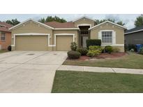 Tan single-Gathering home with a well-maintained lawn and a two-car garage at 11318 Laurel Brook Ct, Riverview, FL 33569