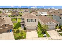 Two-story home in a suburban community, showcasing a well-manicured lawn, a driveway, and a two-car garage at 17006 Wave Tressle Pl, Wimauma, FL 33598