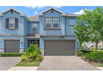 Charming townhome with blue exterior, well-maintained landscaping, and a two-car garage at 18872 Noble Caspian Dr, Lutz, FL 33558