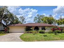 Beautiful one-story home with a lush front lawn, mature trees, and an attached two-car garage at 23059 Geneva Rd, Land O Lakes, FL 34639