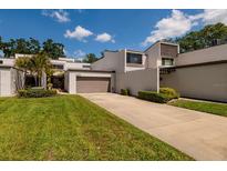 Modern home featuring a two-car garage, well-maintained lawn, and clean, white stucco facade at 4207 Fairway Run, Tampa, FL 33618