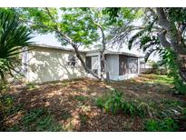 Shaded backyard featuring a screened in lanai, and mature trees at 9130 Dresden Ln, Port Richey, FL 34668