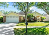 Charming yellow home with a well-manicured lawn, lush landscaping and an attached two car garage at 10602 Rochester Way, Tampa, FL 33626