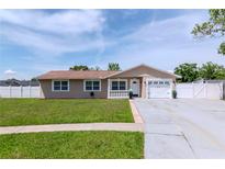 Charming single-story home with a well-manicured lawn, a white picket fence, and an attached two-car garage at 10705 Knollsway Ct, Tampa, FL 33625