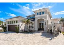 Stunning two-story home featuring a gray exterior, double doors, manicured landscaping, and a brick driveway at 182 E Canal Dr, Palm Harbor, FL 34684