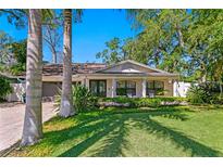 Charming home features a well-manicured lawn and inviting front porch with decorative pillars at 207 S Coolidge Ave, Tampa, FL 33609