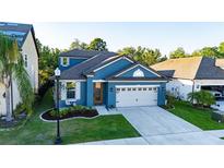Elevated view of a lovely blue home with manicured lawn and a two-car garage at 30647 Walker Cup Pl, Wesley Chapel, FL 33543