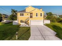 Charming yellow two-story home with a well-manicured lawn, driveway, and a boat parked on the side at 4116 Diaz Ct, Hernando Beach, FL 34607