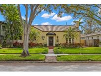 Charming yellow home featuring a Spanish tile roof, manicured lawn, and mature landscaping at 646 16Th Ne Ave, St Petersburg, FL 33704