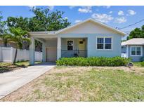 Charming blue bungalow with a covered porch, yellow front door, and an attached garage at 7113 S Mascotte St, Tampa, FL 33616