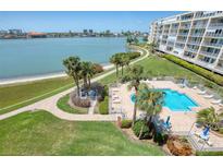 Inviting community pool with palm trees, lounging area, and waterfront view at 7872 Sailboat Key S Blvd # 404, South Pasadena, FL 33707