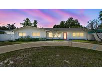 Charming single-story home with a well-manicured front yard, circular driveway, and a striking red front door at 827 Virginia St, Dunedin, FL 34698