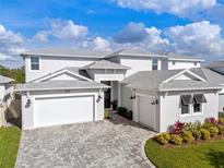 Stunning elevation showcasing a 3-car garage and beautifully landscaped front yard at 8720 Drummer Plank Dr, Wesley Chapel, FL 33545
