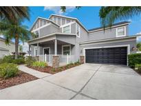 Charming two-story home with a front porch, a two-car garage, and landscaped yard at 9607 Orange Jasmine Way, Tampa, FL 33647