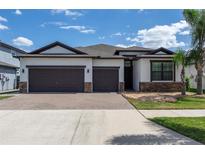 Charming single-story home with a well-manicured lawn, brick-paved driveway, and a three-car garage at 10008 Celtic Ash Dr, Ruskin, FL 33573