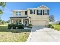 Inviting two-story home with a manicured lawn, covered porch, and attached two-car garage at 36139 Carriage Pine Ct, Zephyrhills, FL 33541