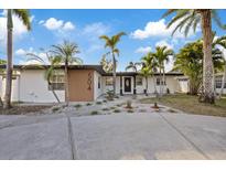 Charming single-story home featuring a well-manicured yard with lush tropical landscaping and an inviting entrance at 504 Driftwood E Dr, Palm Harbor, FL 34683
