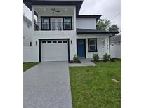 Two-story home with white exterior, black trim, balcony, blue front door, well-kept lawn and driveway at 5730 66Th Ln N, St Petersburg, FL 33709